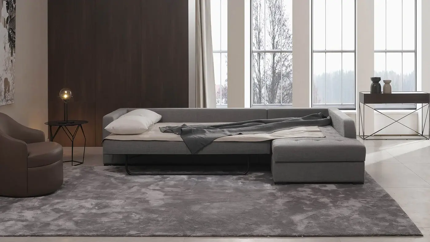 یک مبل تختخوابشو طوسی رنگ که به صورت ال قرار گرفته و در دکوراسیون داخلی منزل تاثیر مثبتی گذاشته است
